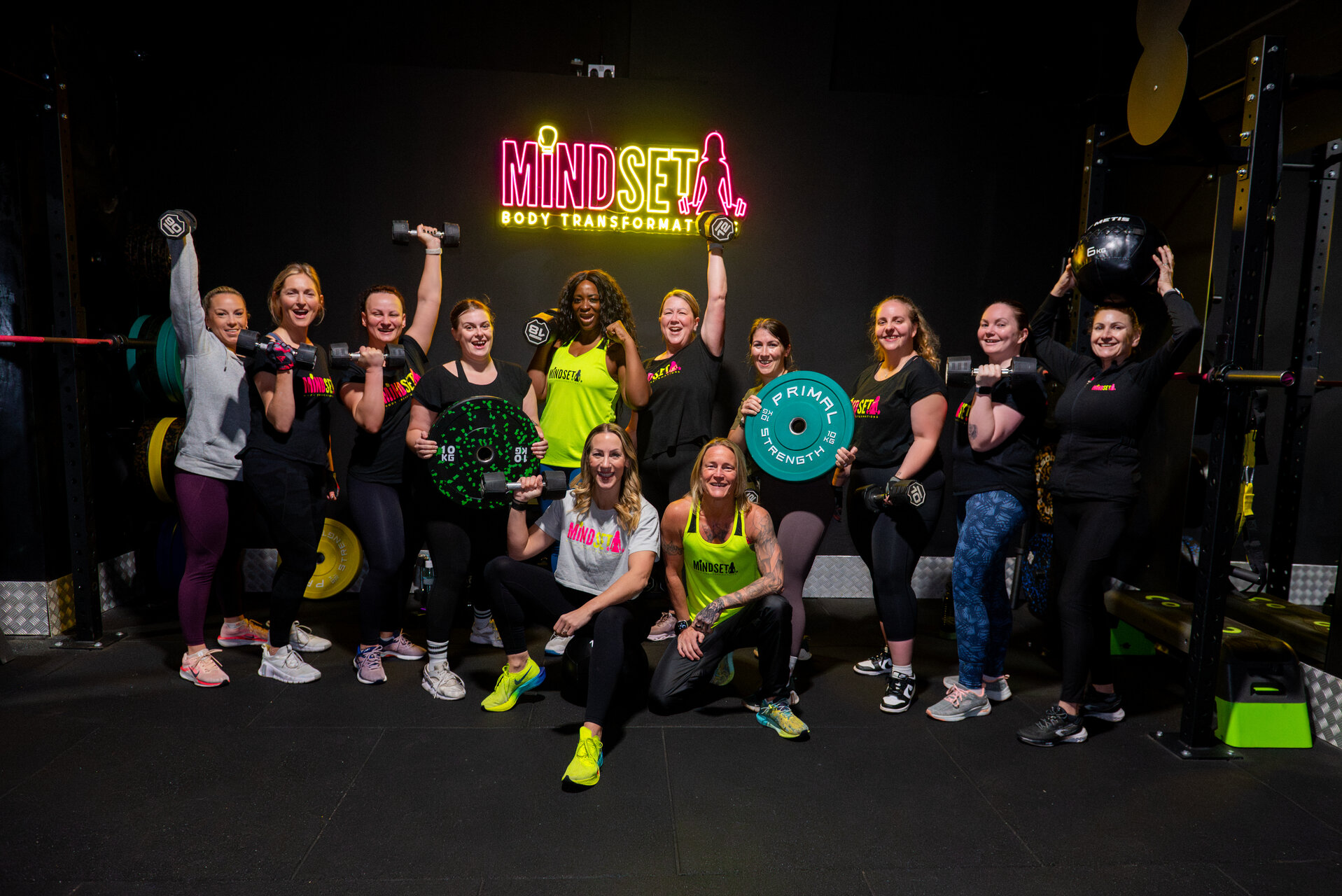 The Mindset Body Transformations community celebrating under the studio neon sign in Southampton